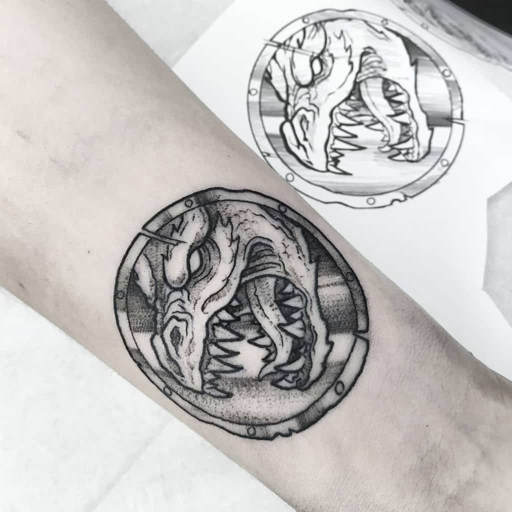 Forearm tattoo of a fierce dragon's head inside a circular frame