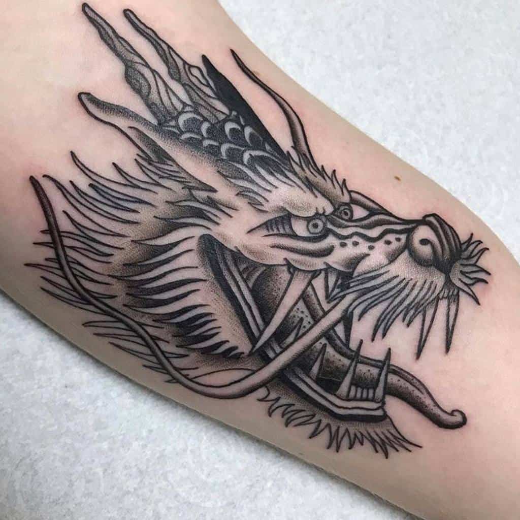 Detailed black and gray dragon tattoo head on the forearm