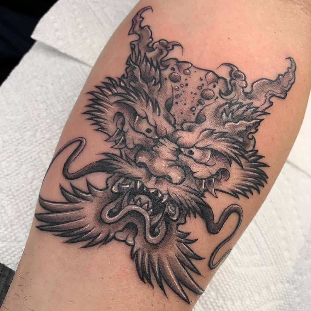 Black and gray tattoo showcasing the fierce head of a dragon on an arm