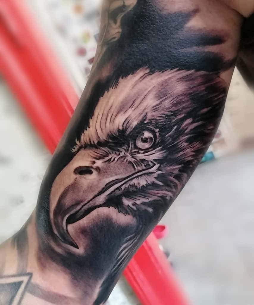 Tattoo of a realistic eagle head with intense detailing on a forearm