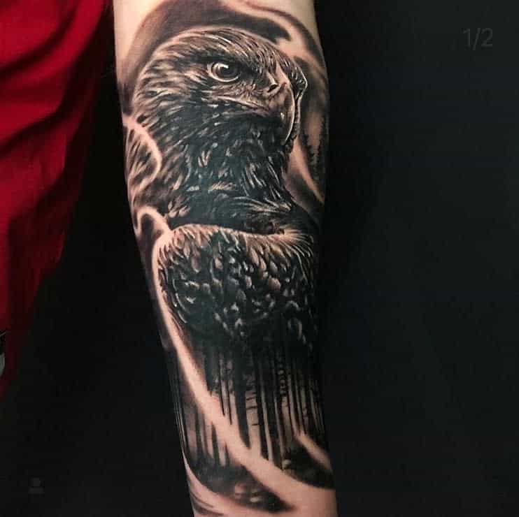 Black and white tattoo of an eagle head with detailed feathers on a forearm