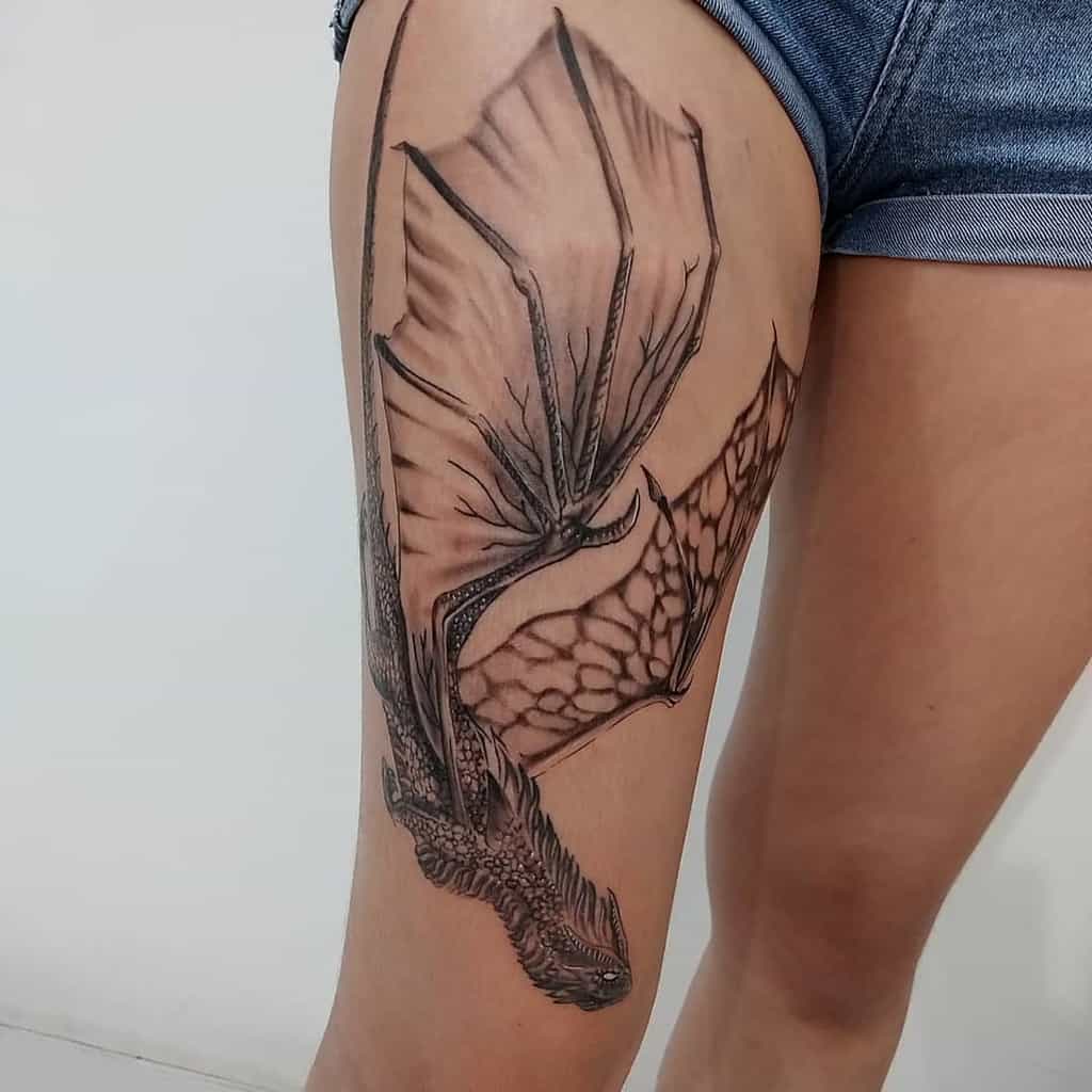 Detailed dragon tattoo on the thigh, inspired by Game of Thrones, featuring intricate scales and large, textured wings