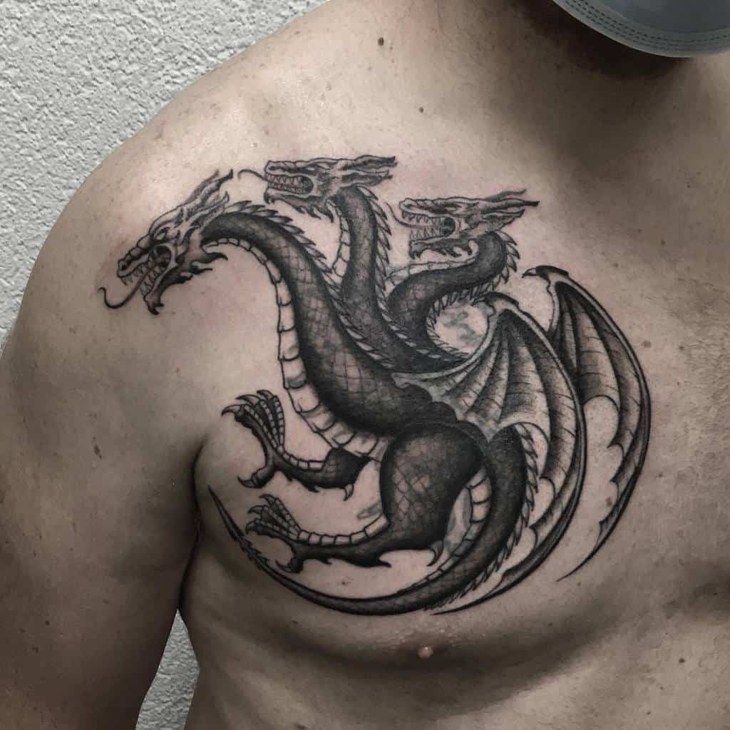Chest tattoo of a three-headed dragon inspired by the Targaryen sigil from Game of Thrones, detailed in black and grey shading