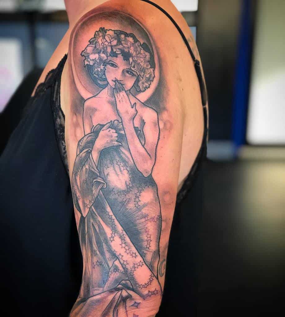 Half sleeve tattoo of a woman with flowers in hair, covering herself with one hand, on a woman's upper arm