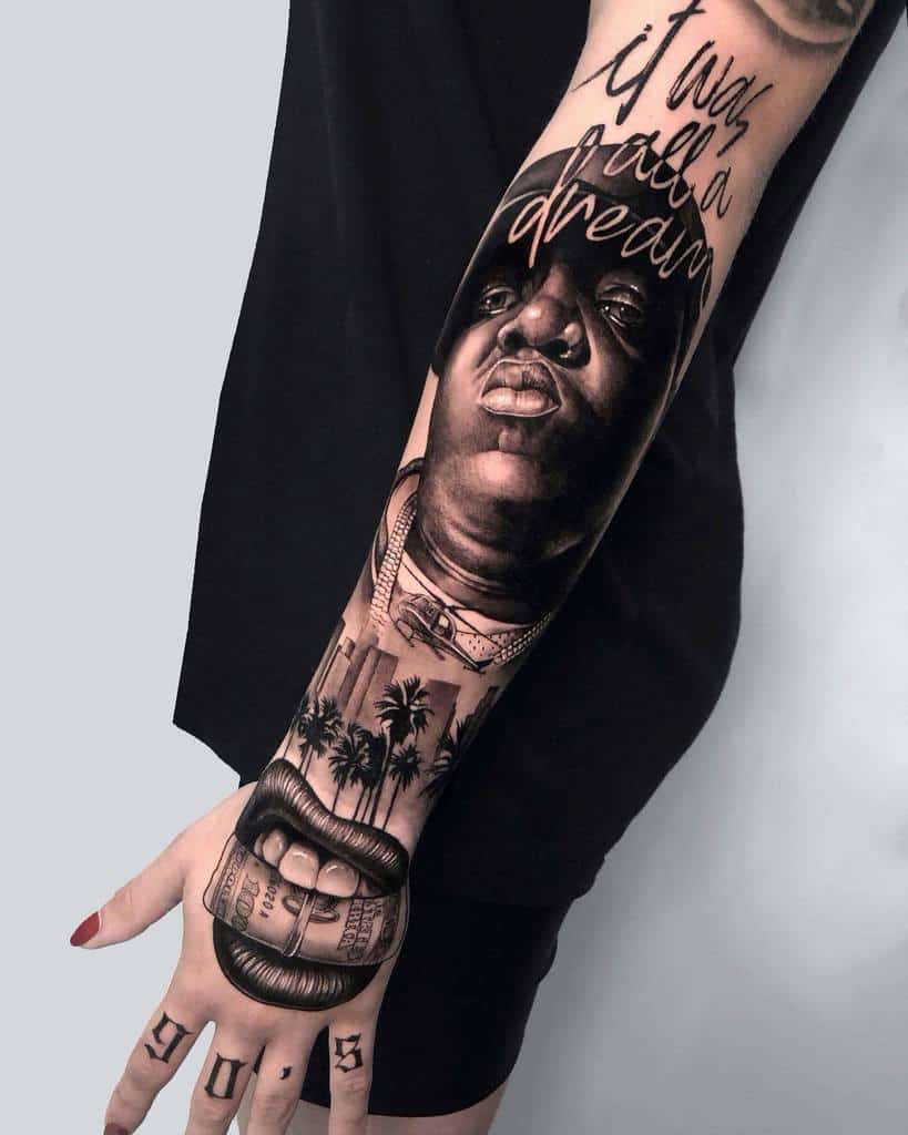 "Detailed black-and-grey sleeve tattoo featuring a portrait, 'It was all a dream' script, palm trees, and dollar bills