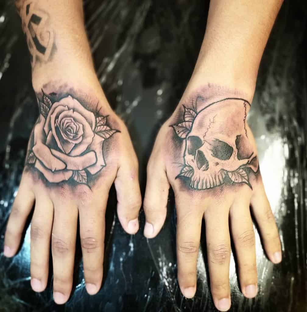 Bold black and grey tattoos featuring a detailed rose and a skull with leaves