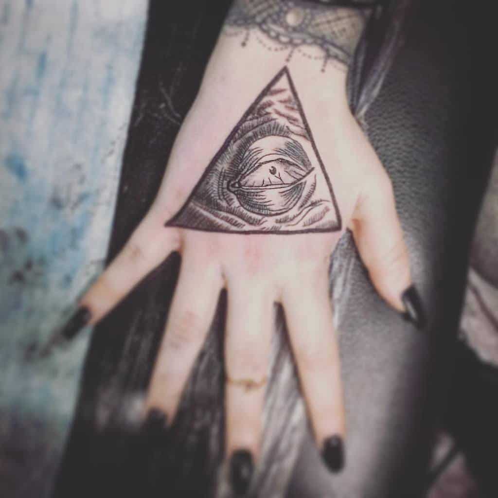 A black tattoo featuring an eye inside a triangle with intricate linework