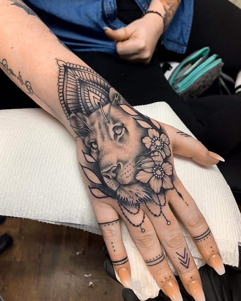 A tattoo featuring a lion's face adorned with flowers and geometric patterns