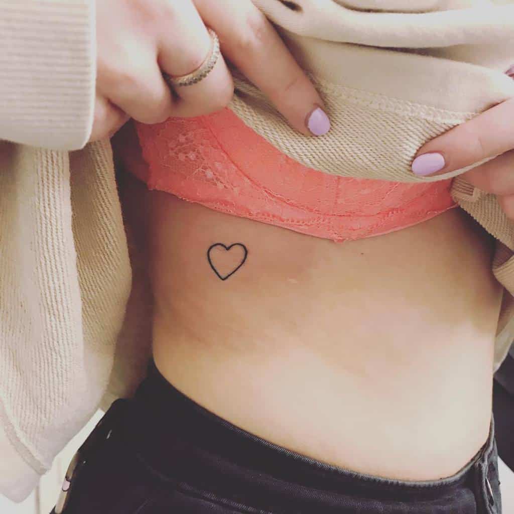 A woman with a heart-shaped outline tattoo on the side of their torso