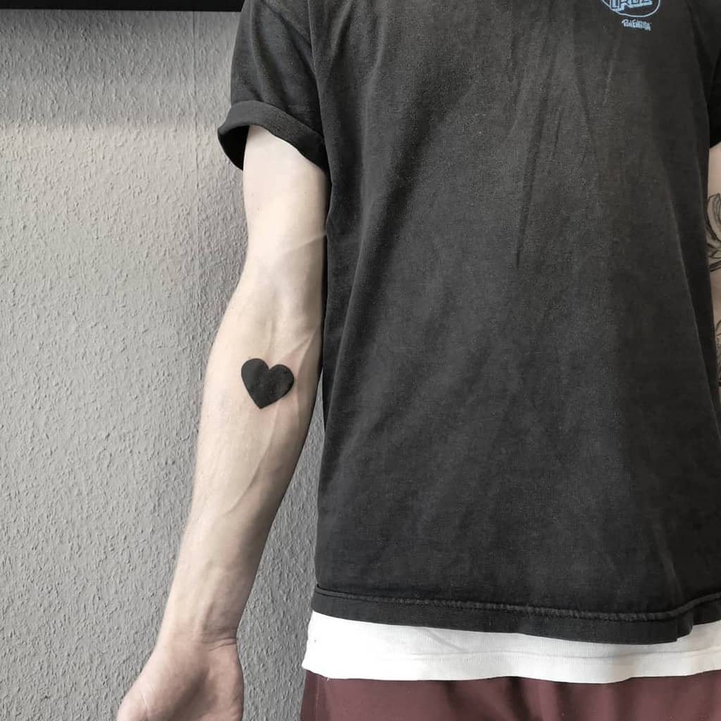 Minimalist solid black heart tattoo creating a bold yet simple statement