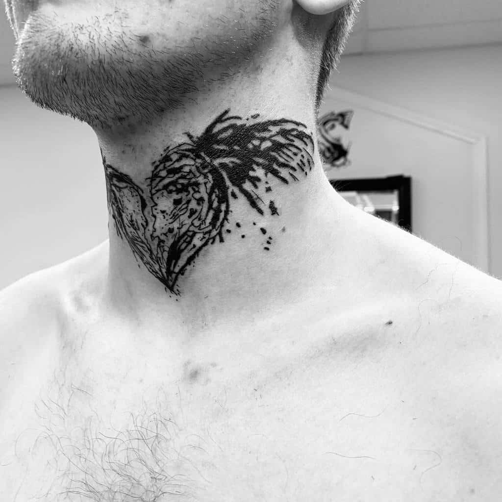 Black heart tattoo featuring intricate leaf-like patterns with splatter details, creating a bold, artistic design