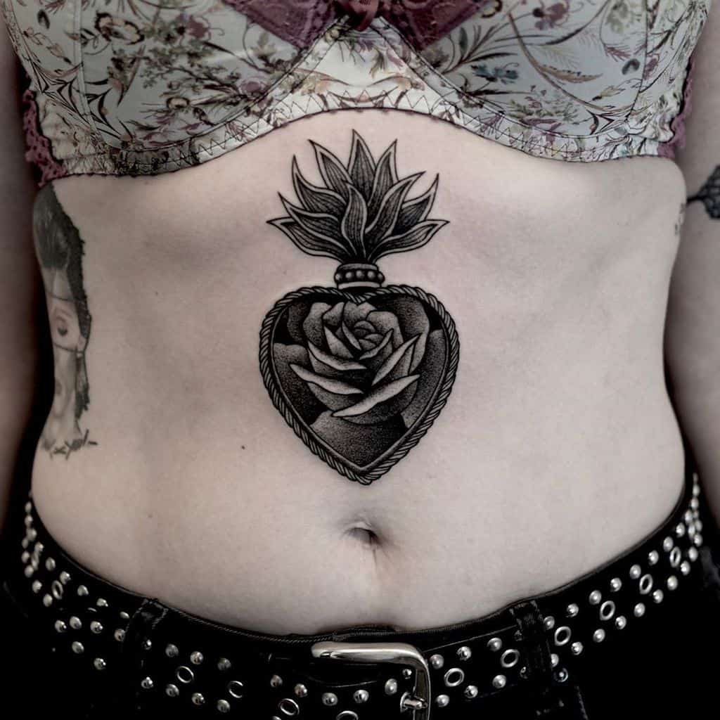 Intricate black heart tattoo, featuring a detailed rose inside and a decorative crown-like top