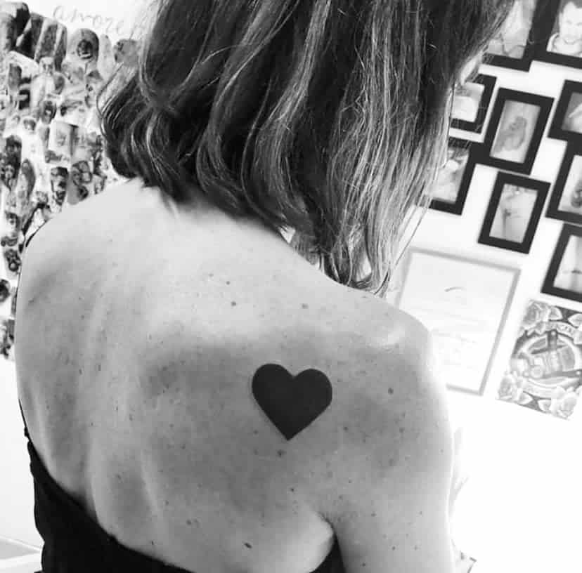 Simple and bold black heart tattoo, showcased in a black and white image