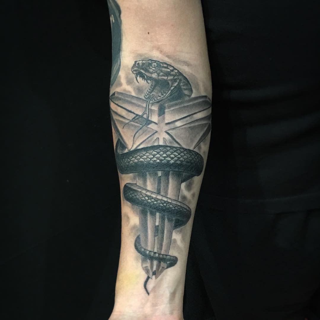 Tattoo of a snake wrapped around a dagger on the inner forearm