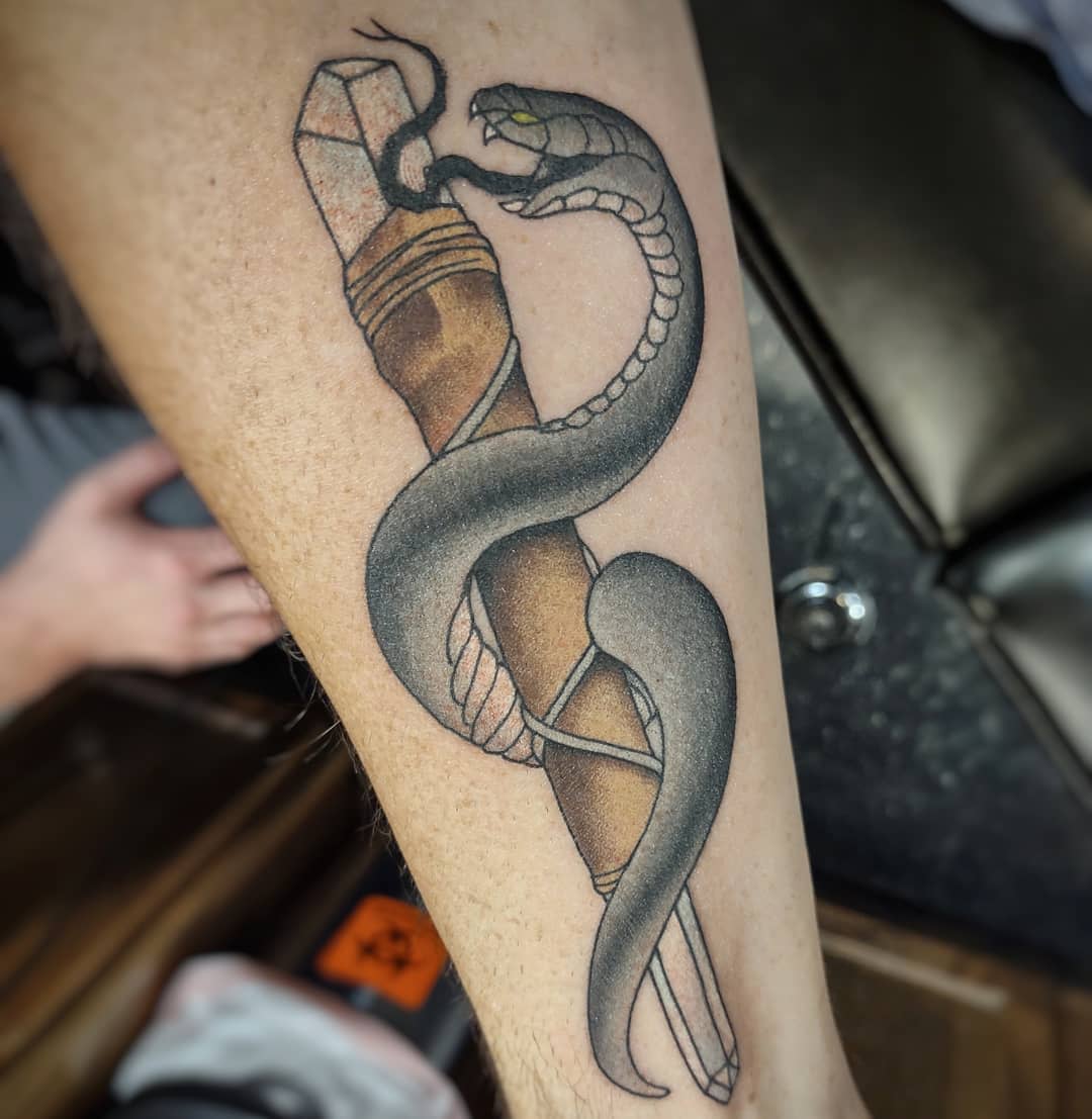 Tattoo of a snake coiled around a crystal on a leg