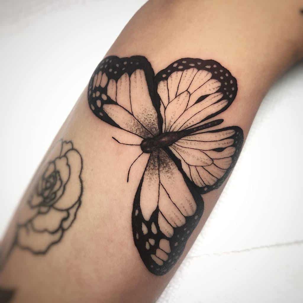 A stunning black and white monarch butterfly tattoo graces the arm