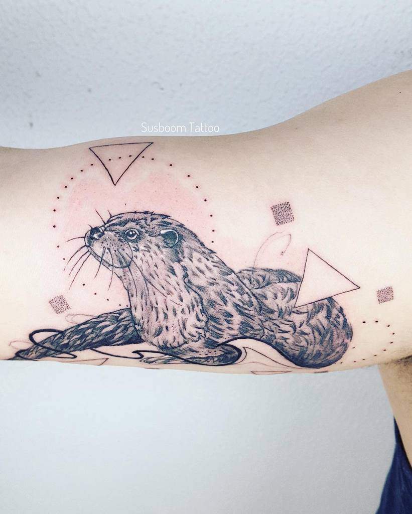 Otter tattoo with triangles and dots, artfully blending natural and abstract elements on the arm