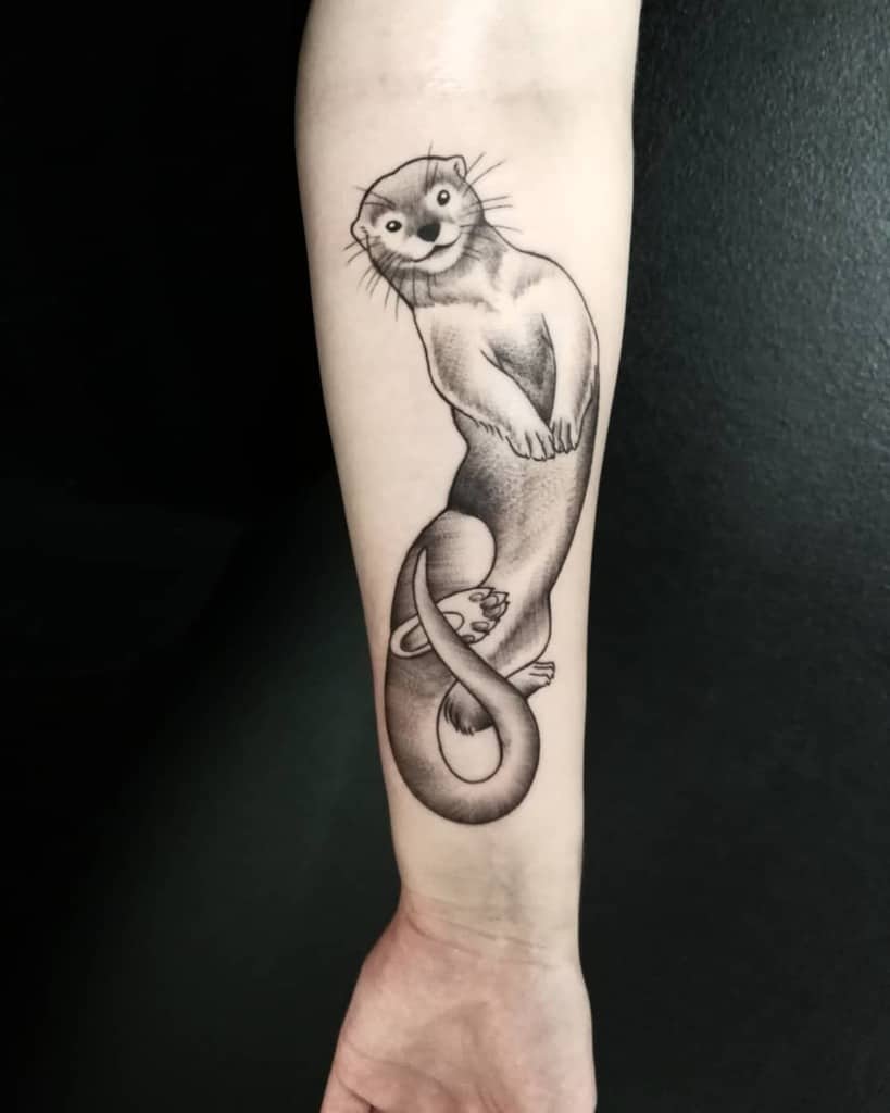 Forearm tattoo of a stylized otter with smooth lines and shading, the playful otter positioned vertically against the skin