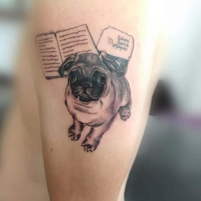 Tattoo of a pug with an open book and text in a note, "Gabriel García Márquez" 