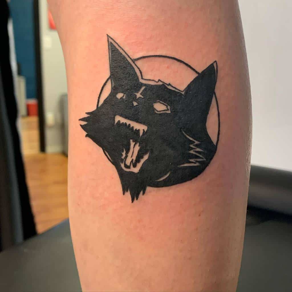 Tattoo of a snarling black cat face on a person's skin