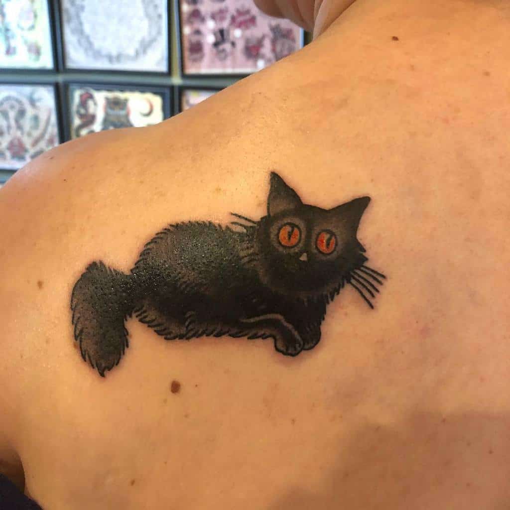 A tattoo of a black cat with red eyes on a shoulder