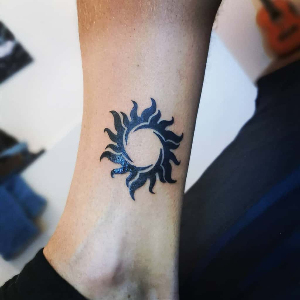 Black sun tattoo on the inner part of a wrist