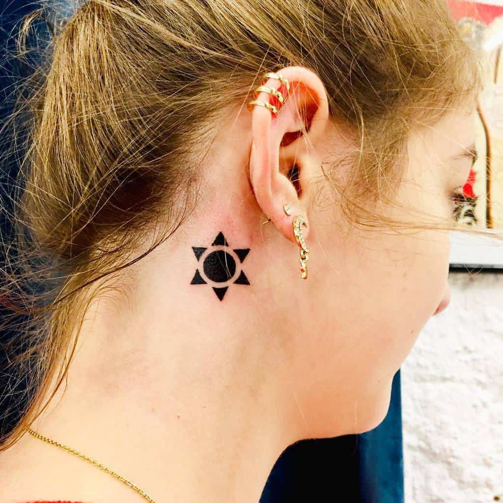 Small geometric sun tattoo behind the ear