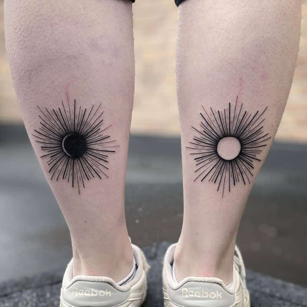 Two calves with matching sunburst tattoos, one with a black center and the other with a blank center