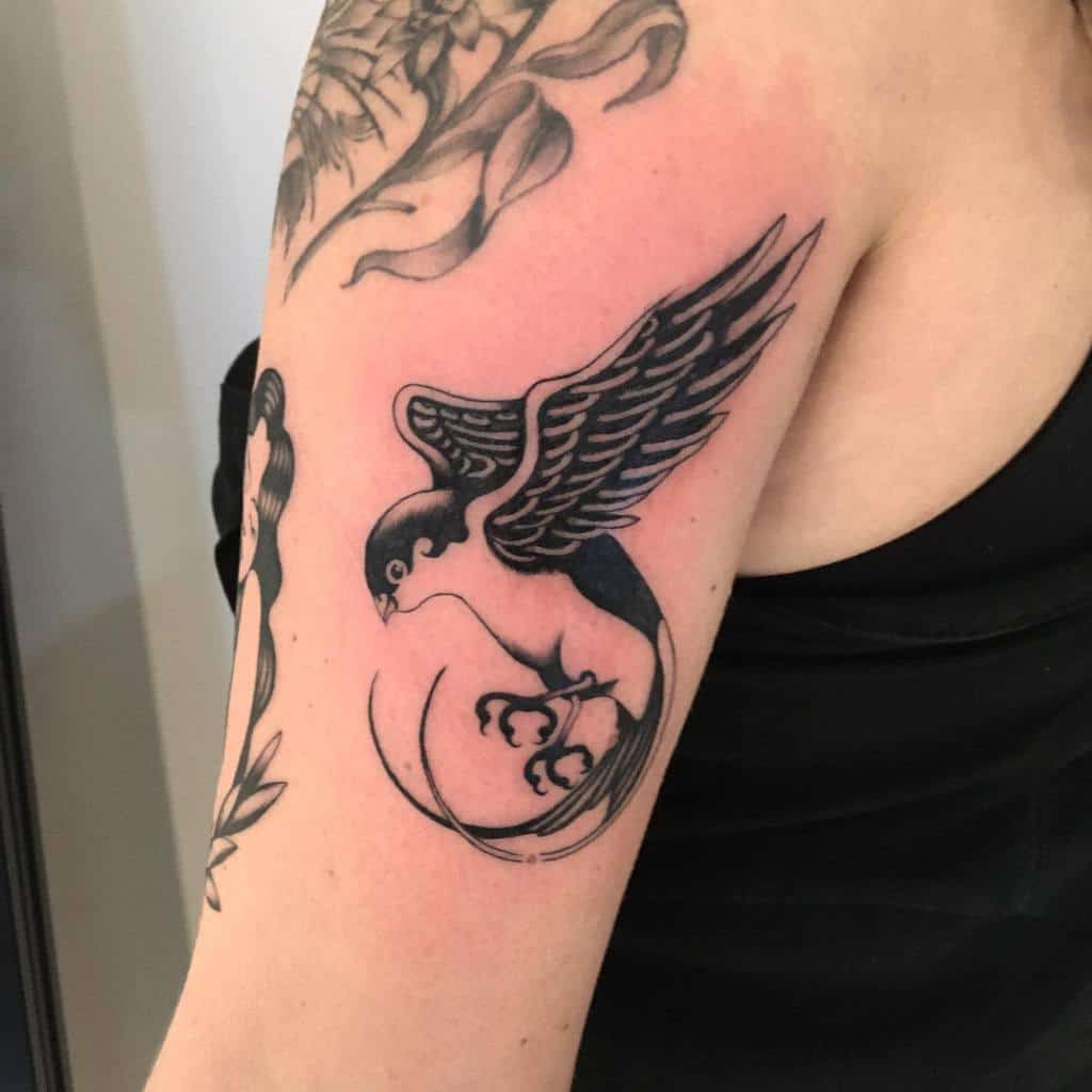 Tattoo of a black bird on an arm, with detailed wing and tail feathers