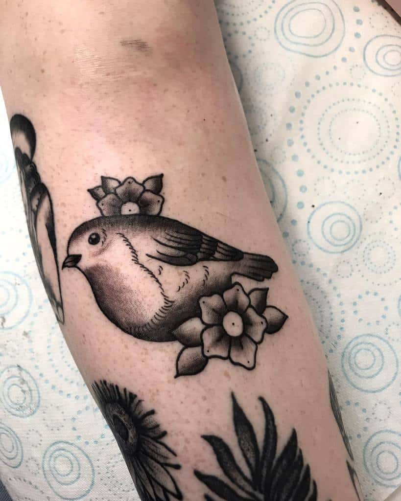 Tattoo of a sparrow and flowers on an arm