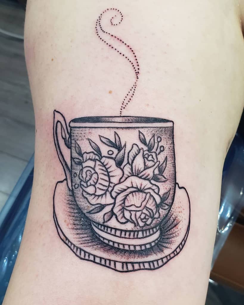 Tattoo of a tea cup with floral design and dotted steam rising 