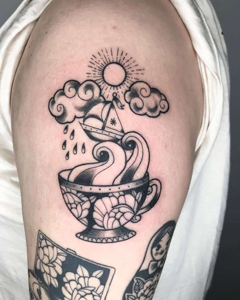 Tattoo of a teacup with waves inside, boat, clouds, raindrops, and a sun above 