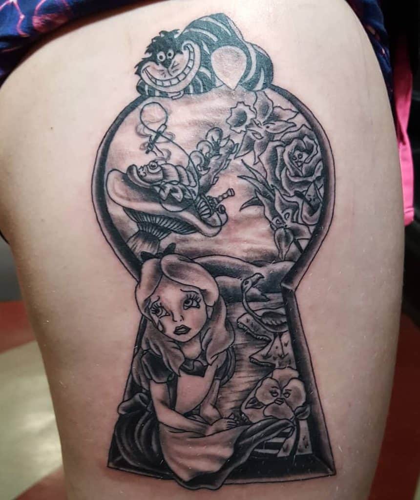 Black and white tattoo featuring Alice from Alice in Wonderland within a keyhole frame, surrounded by the Cheshire Cat, playing cards, roses, and whimsical elements