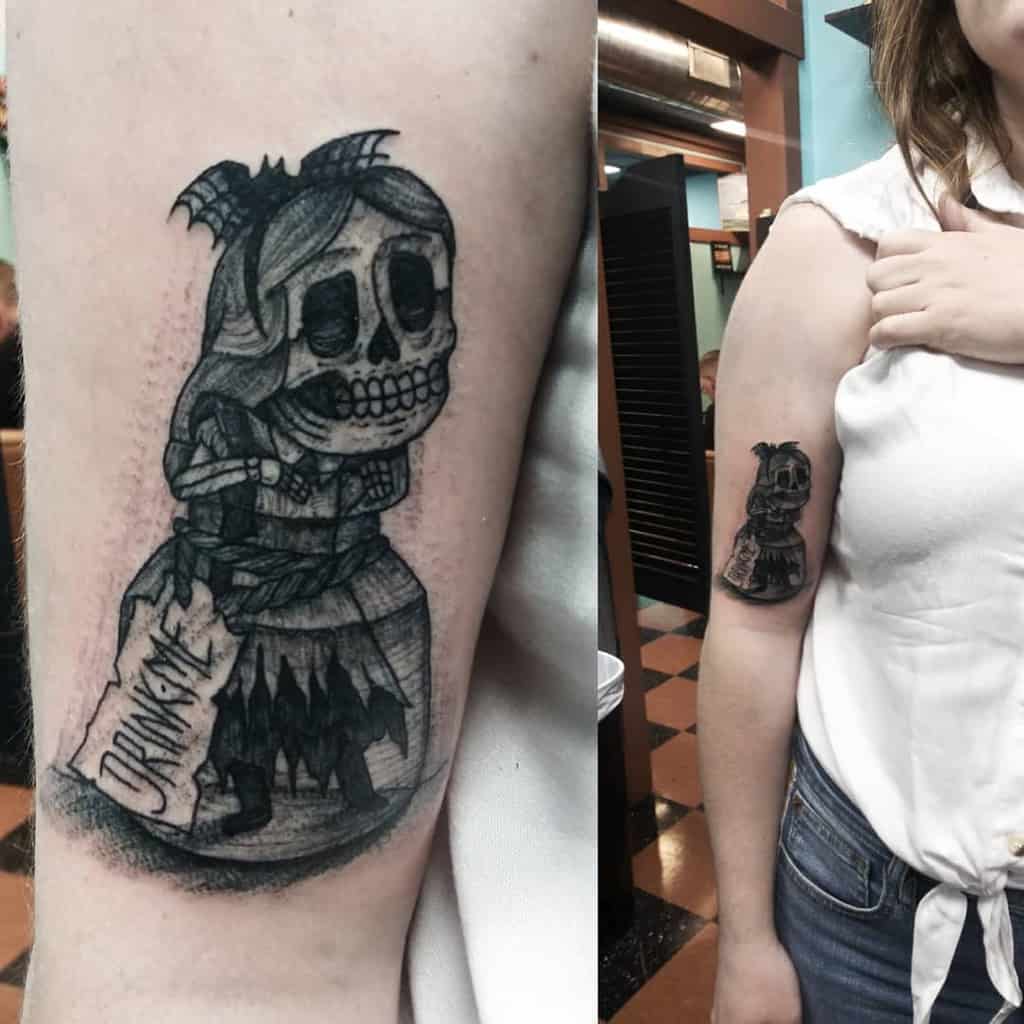 Black and white tattoo of a skeleton version of Alice from Alice in Wonderland, inside a bottle labeled 'Drink Me'
