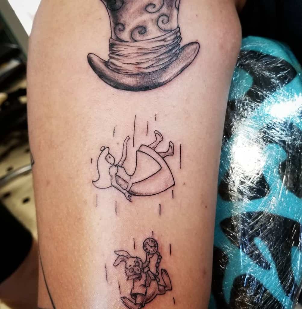 Black and white tattoo featuring the Mad Hatter’s hat, Alice falling down the rabbit hole, and the White Rabbit running with a pocket watch