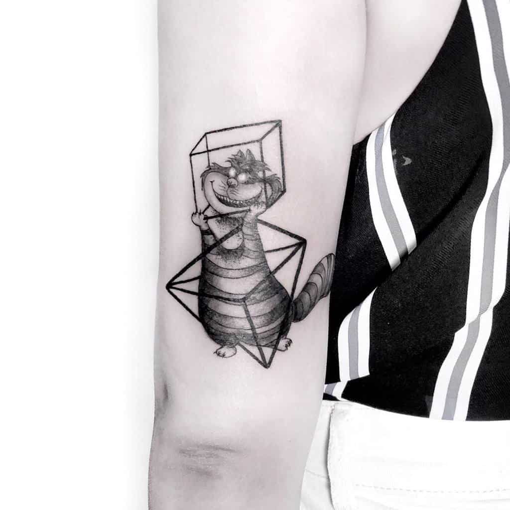Black and gray tattoo of the Cheshire Cat from Alice in Wonderland, surrounded by geometric shapes, with its mischievous grin and striped body