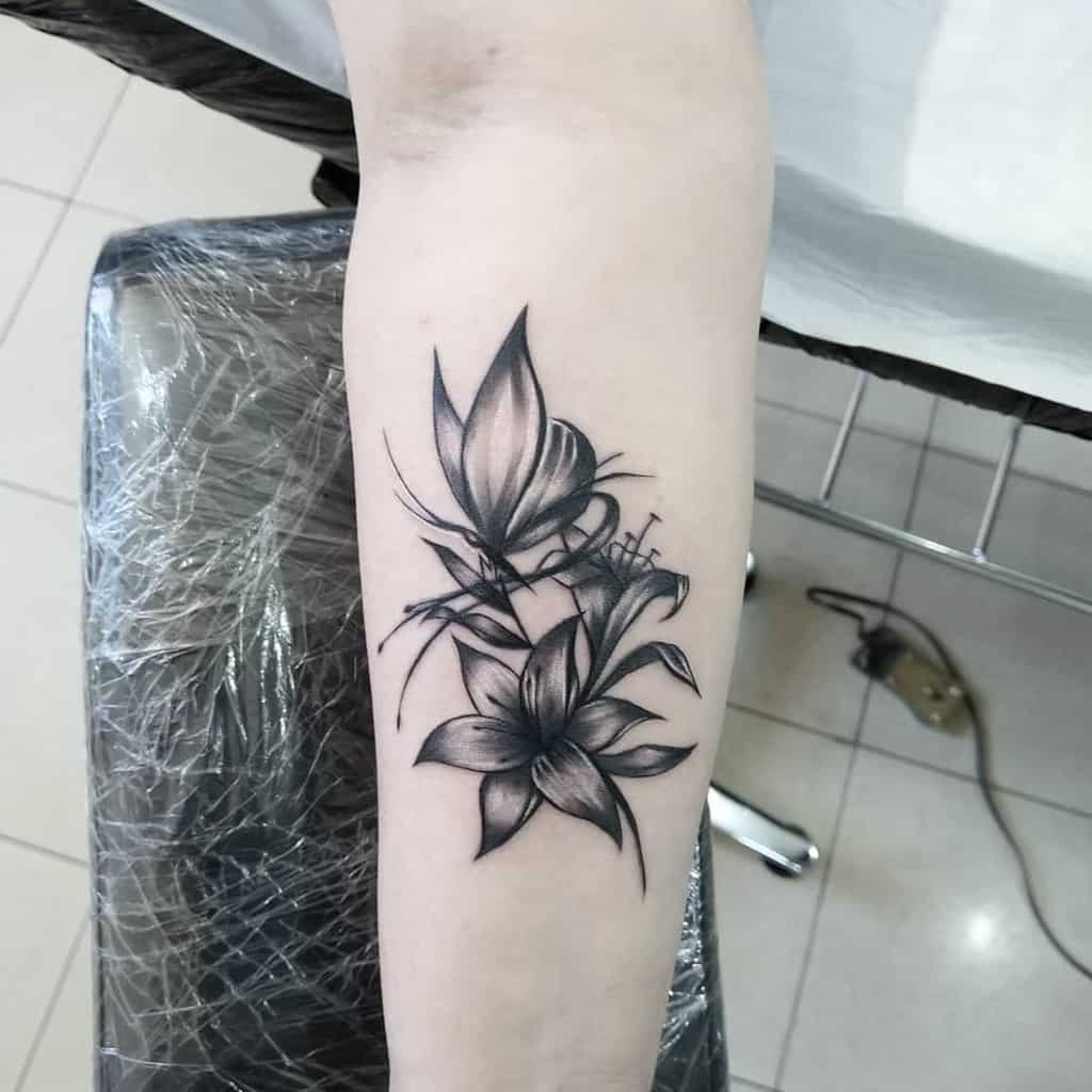 Elegant black and grey tattoo of blooming lilies with fine shading and soft gradients, symbolizing beauty, purity, and resilience