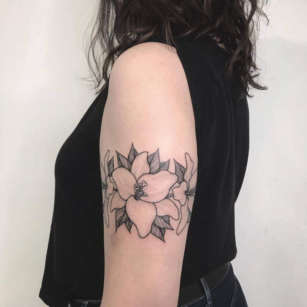 Elegant black and grey tattoo of blooming lilies with bold outlines and fine shading, symbolizing purity, strength, and beauty