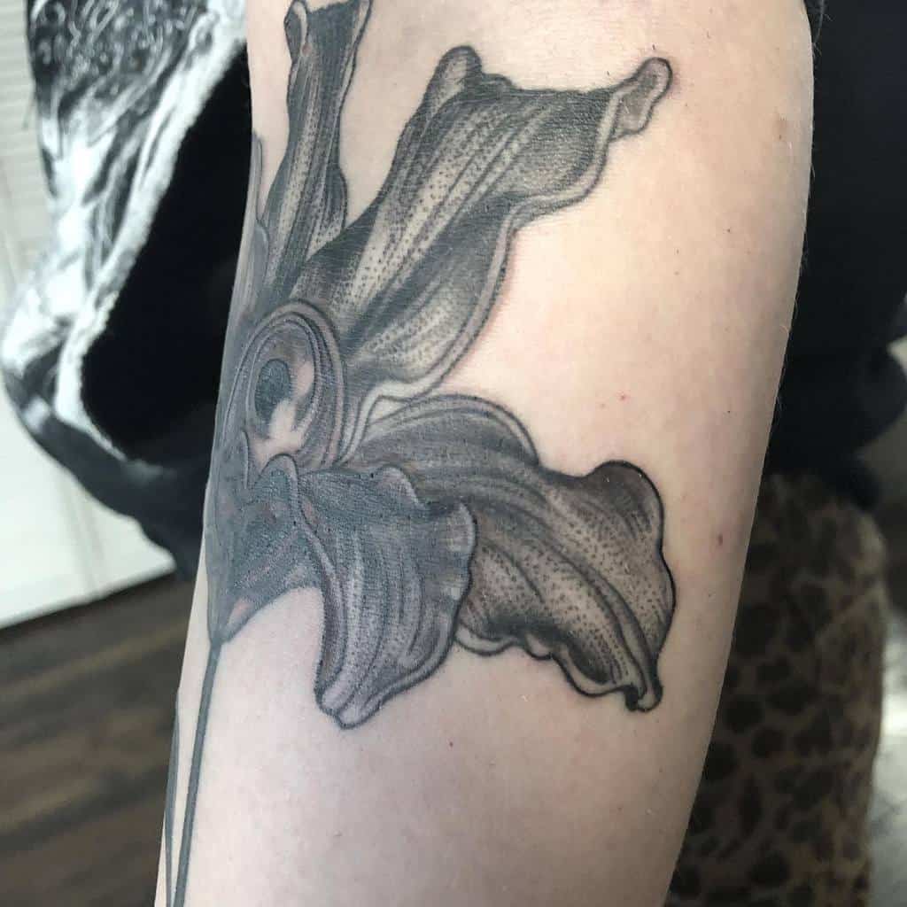 Detailed black and grey tattoo of a lily with bold shading and fine dot work, creating a striking and artistic floral design
