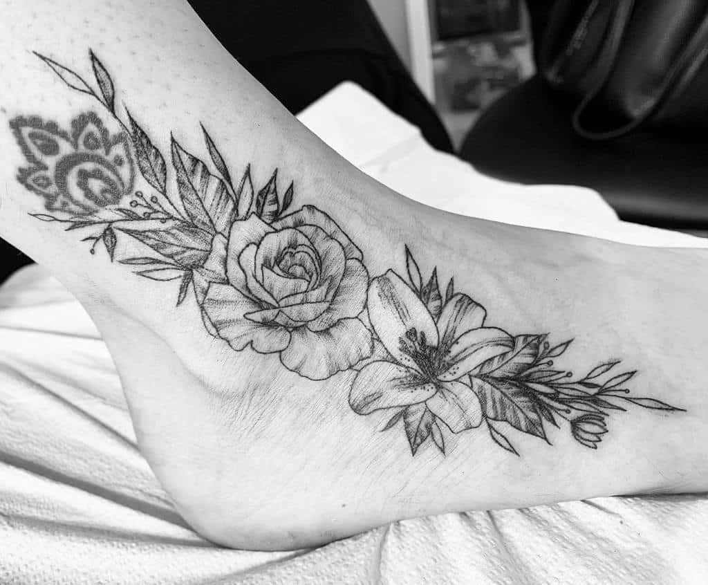 Elegant black and grey tattoo of a rose and lily intertwined with leaves and delicate details