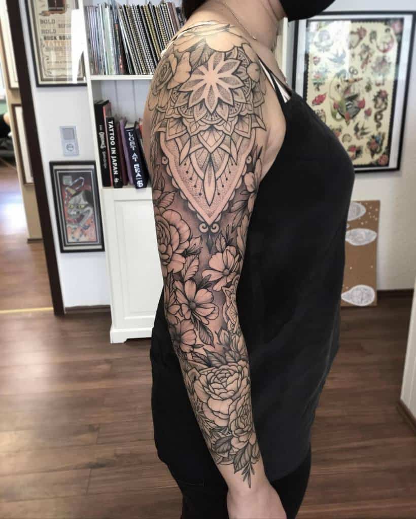 Woman showcasing an intricate floral and mandala sleeve tattoo on her arm