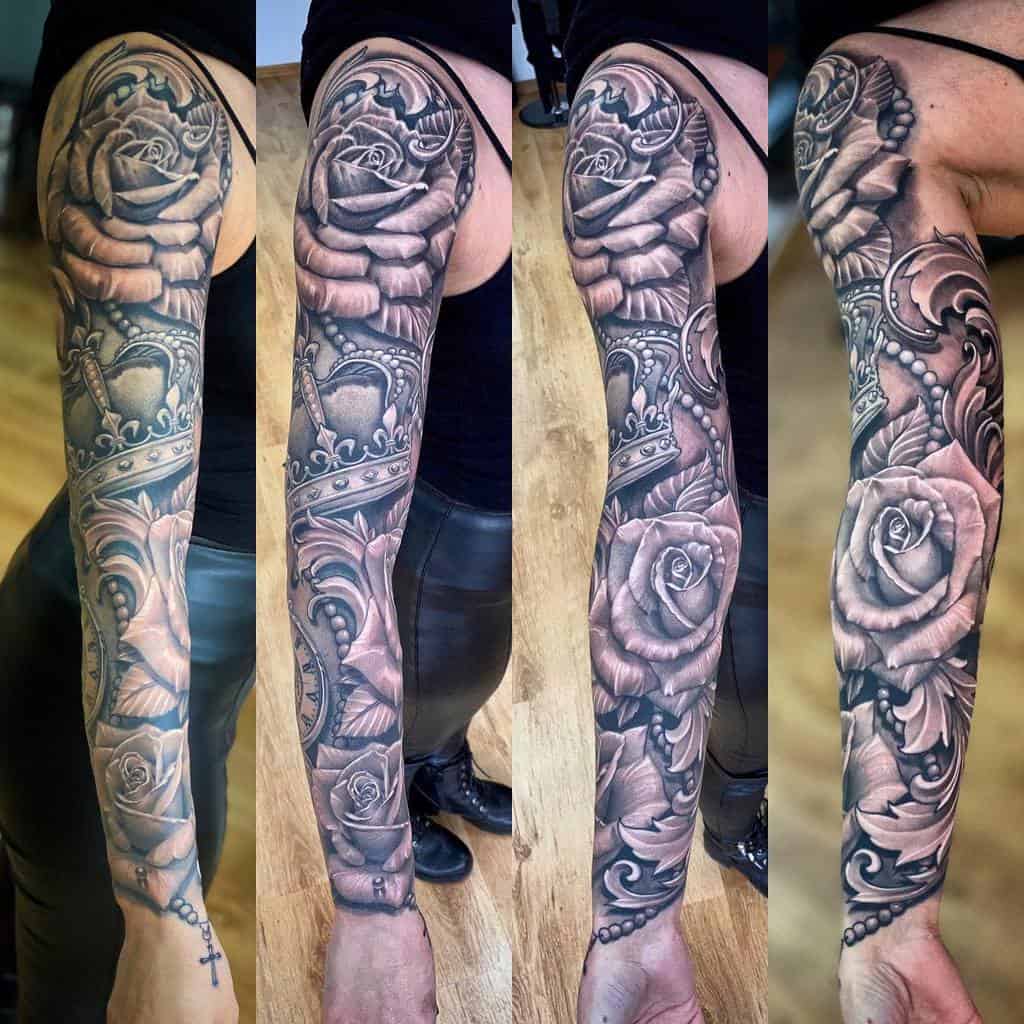 Detailed black-and-white sleeve tattoo showcasing roses, crowns, and ornate patterns with a feminine and elegant style