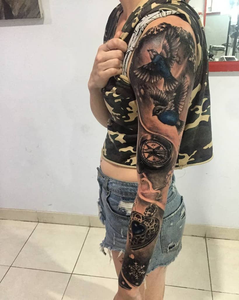 Elegant black-and-white sleeve tattoo featuring birds in flight, a compass, and intricate pocket watch details