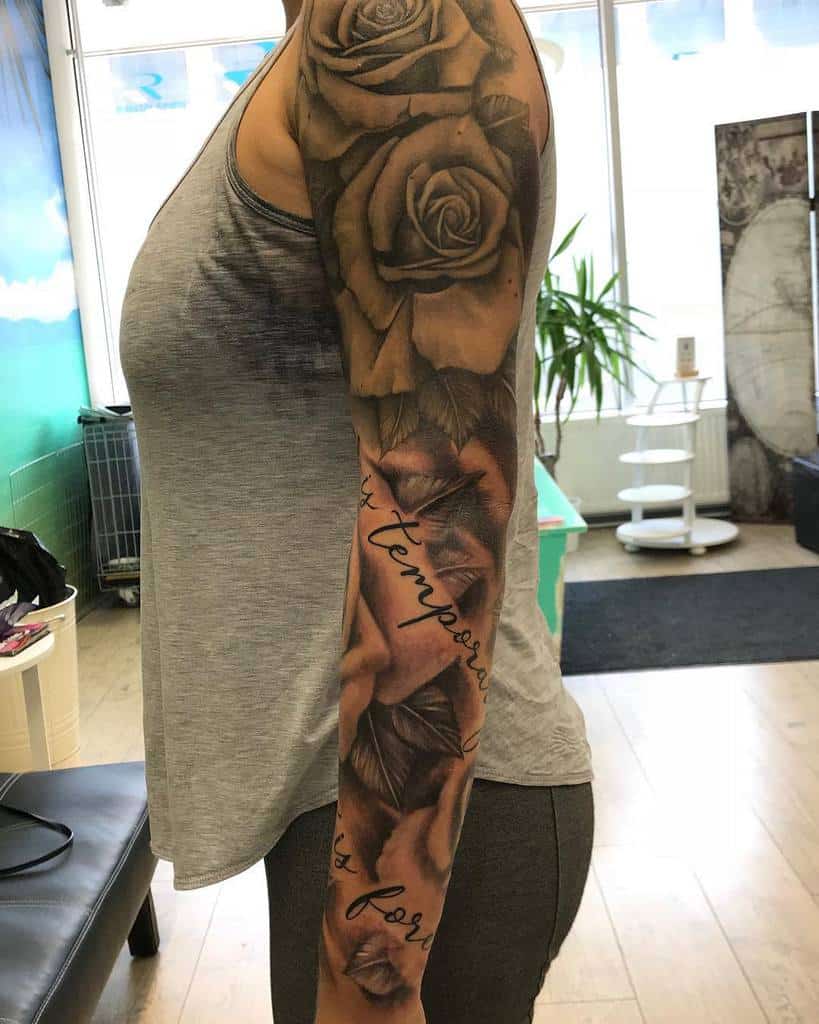 Woman with a detailed rose sleeve tattoo on left arm