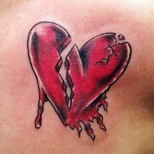 A tattoo of a heart with cracks and jagged edges, bleeding red onto the skin