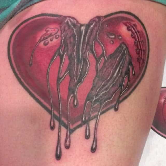 Tattoo of a bleeding heart with a cracked center and dripping details