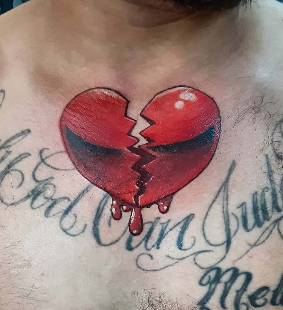 A chest tattoo featuring a broken, bleeding red heart, encircled by elegant cursive black lettering
