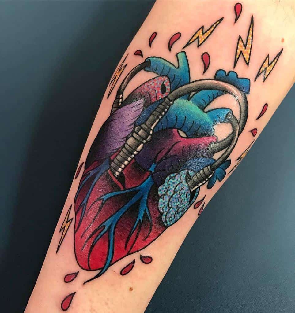 Tattoo of a bleeding anatomical heart with detailed veins, arteries, and vibrant colors on an arm