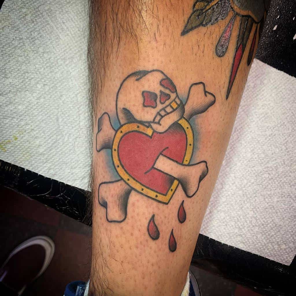 Tattoo of a skull and crossbones with a bleeding heart and dripping blood on a person's forearm