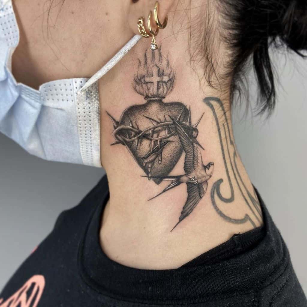 Tattoo of a flaming, bleeding Sacred Heart with thorns and a swallow on the side of a person's neck